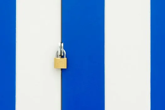 Padlock securing a blue and white striped door, symbolizing safety.