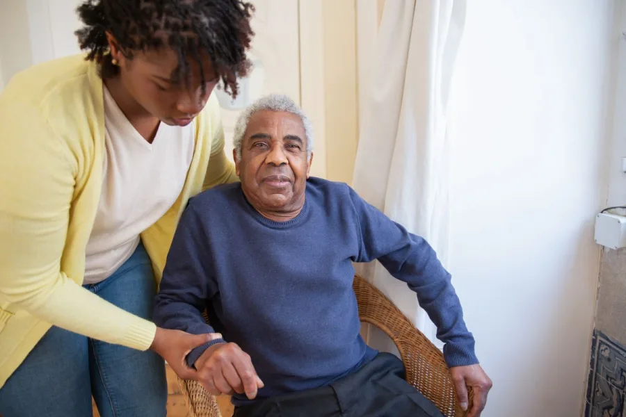 Caregiver assisting elderly woman in her home with warmth and patience